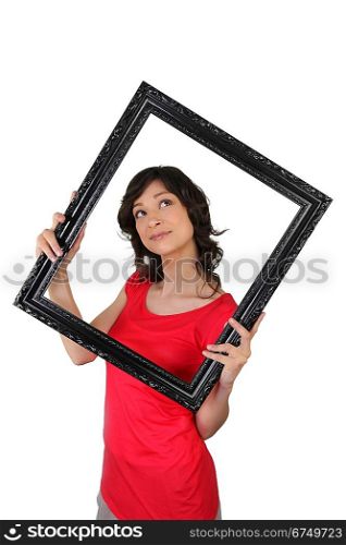 Young woman carrying black frame, studio shot