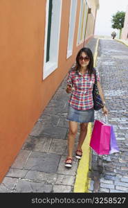 Young woman carrying shopping bags and holding a mobile phone, Old San Juan, San Juan, Puerto Rico