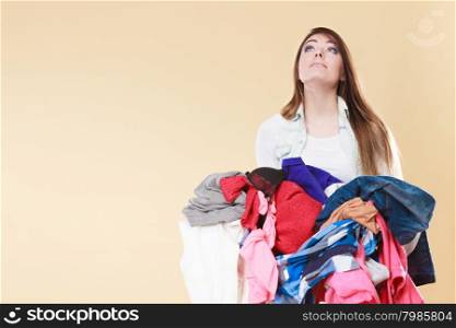 Young woman carrying stack pile of dirty laundry clothes. Girl cleaning tidying in studio.