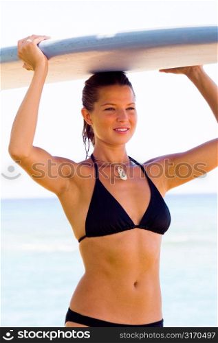 Young Woman Carrying Surf Board on Her Head