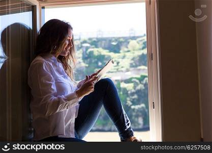 Young woman catching some sun at the balcony and checking the social networks