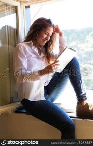 Young woman catching some sun at the balcony and checking the social networks