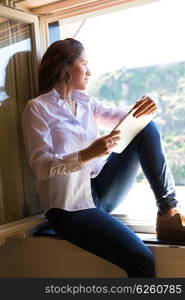 Young woman catching some sun at the balcony and checking the social networks