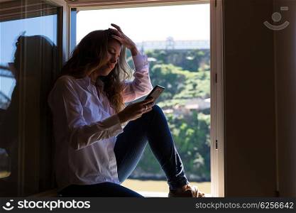 Young woman catching some sun at the balcony while using her new smartphone