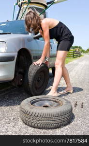 Young woman changing a flat tire