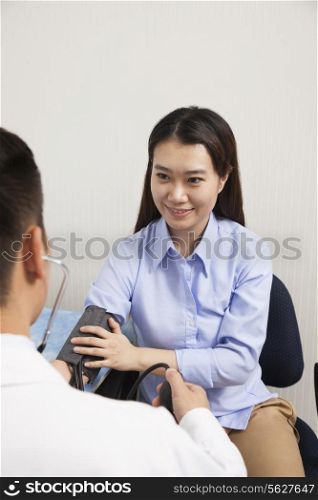 Young Woman Checking Blood Pressure With Male Doctor