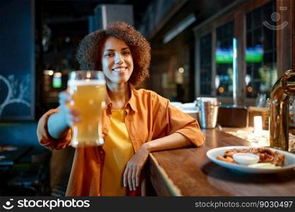 Young woman cheering for favorite team watching match in sports bar. Cheerful excited millennial girl sport fan drinking beer while sitting at counter desk. Young woman cheering for favorite team watching match in sports bar