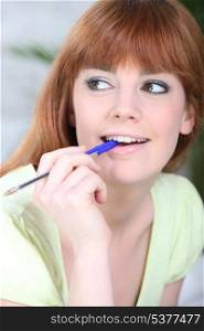 Young woman chewing on a pen