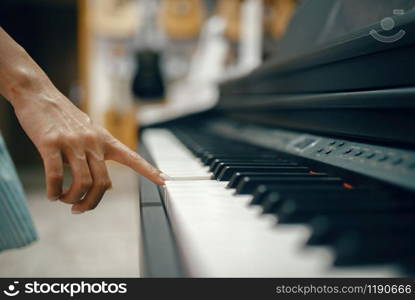 Young woman choosing digital piano in music store. Assortment in musical instrument shop, female musician buying equipment. Young woman choosing digital piano in music store