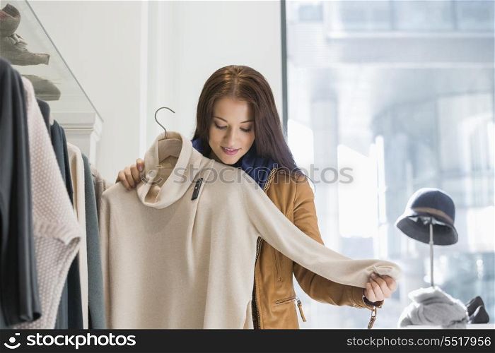 Young woman choosing sweater in store
