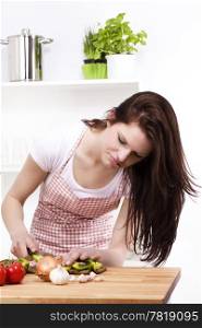 young woman chopping vegetables. young woman looking at the paprika she is chopping for salad