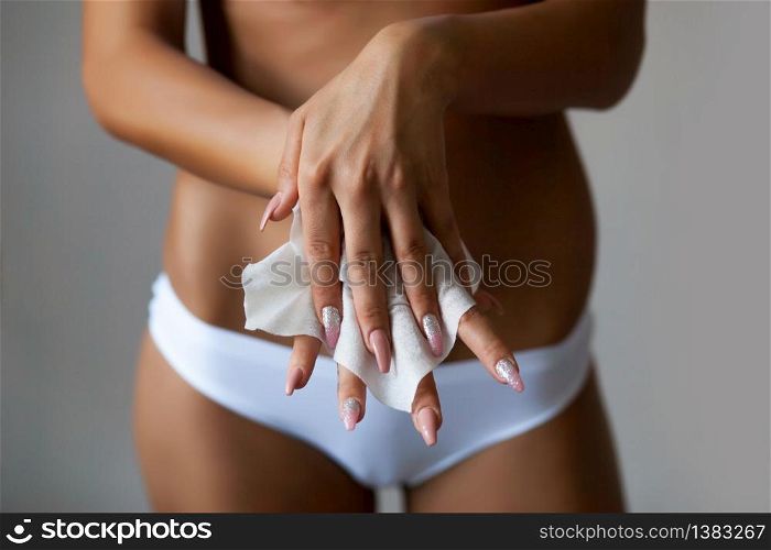 Young woman clean hands with wet wipes, body and panties in background