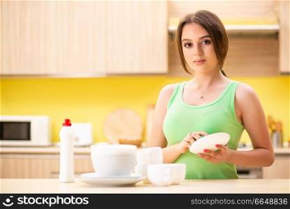 Young woman cleaning and washing dishes in kitchen