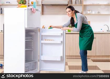 Young woman cleaning fridge in hygiene concept 