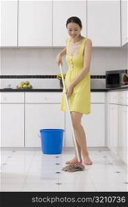 Young woman cleaning the floor with a mop