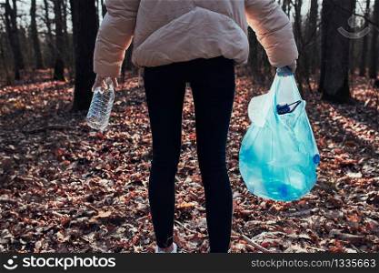 Young woman cleaning up a forest. Volunteer picking plastic waste to bags. Concept of plastic pollution and too many plastic waste. Environmental issue. Environmental damage. Responsibilitiy for environment. Real people, authentic situations