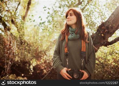 Young woman closeup with old film camera in her hip in the forest