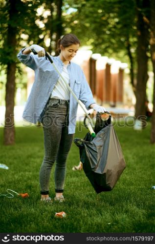 Young woman collects garbage in plastic bag in park, volunteering. Male person cleans forest, ecological restoration, eco lifestyle, trash collection and recycling, ecology care, environment cleaning. Young woman collects garbage in plastic bag