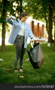 Young woman collects garbage in plastic bag in park, volunteering. Male person cleans forest, ecological restoration, eco lifestyle, trash collection and recycling, ecology care, environment cleaning. Young woman collects garbage in plastic bag