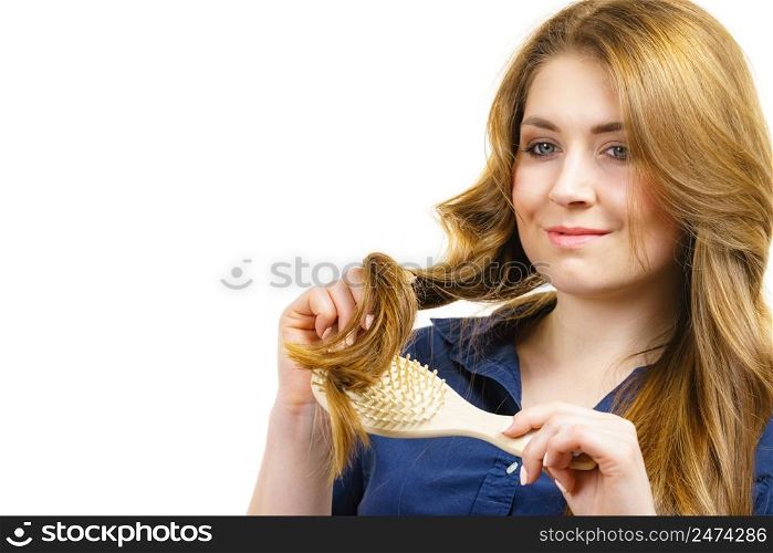 Young woman combing long healthy brown hair, using brush. Haircare. Woman brushing long healthy brown hair