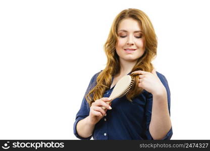 Young woman combing long healthy brown hair, using brush. Haircare. Woman brushing long healthy brown hair