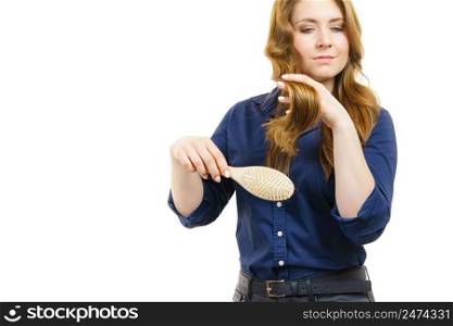 Young woman combing long healthy brown hair, using brush. Haircare. Woman brushing long healthy brown hair