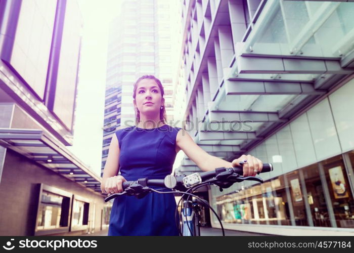 Young woman commuting on bicycle. Young woman in business wear commuting on bicycle in city