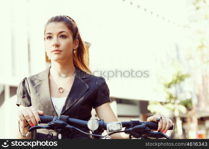 Young woman commuting on bicycle. Young woman in business wear commuting on bicycle in city