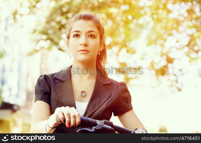 Young woman commuting on bicycle. Young woman in business wear commuting on bicycle in city