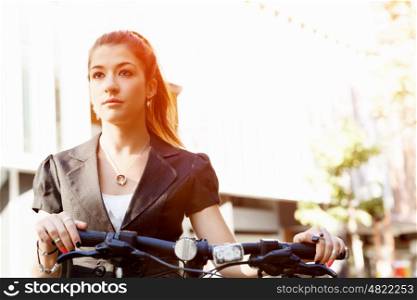 Young woman commuting on bicycle. Young woman in business wear commuting on bicycle in city