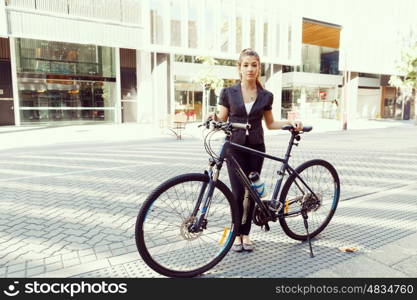 Young woman commuting on bicycle. Young woman in business wear commuting on bicycle in city