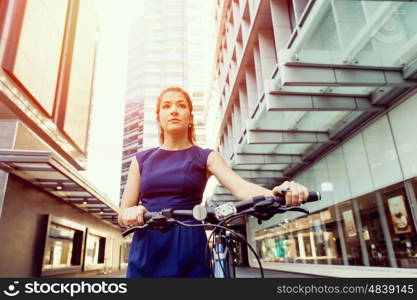 Young woman commuting on bicycle. Young woman in business wear commuting on bicycle in city