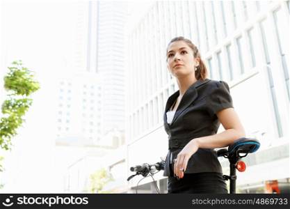 Young woman commuting on bicycle. Young woman in business wear commuting on bicycle in city
