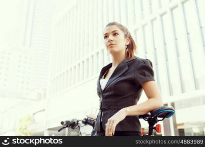 Young woman commuting on bicycle. Young woman in business wear commuting on bicycle in city