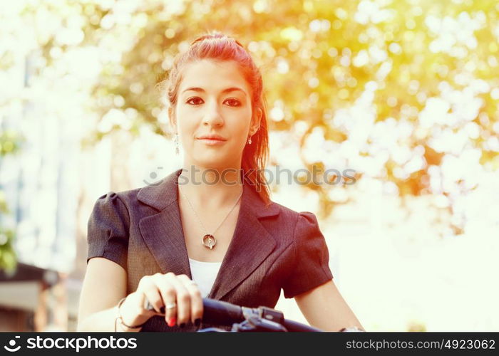 Young woman commuting on bicycle. Young woman in business wear commuting on bicycle in city