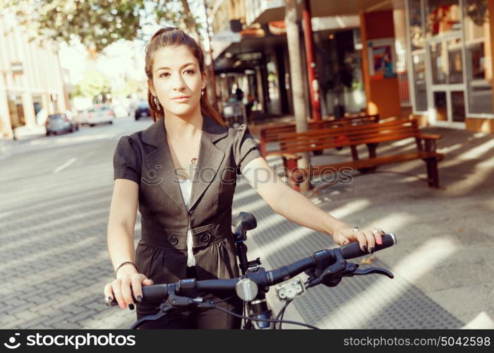 Young woman commuting on bicycle. Young woman in business wear commuting on bicycle in city