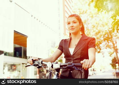 Young woman commuting on bicycle. Young woman in business wear commuting on bicycle in city