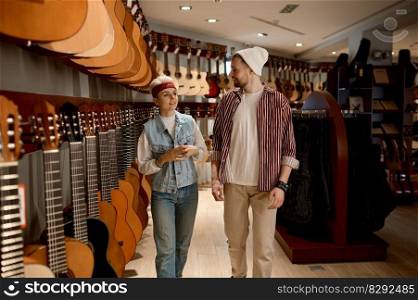 Young woman consultant talking to man buyer advising how to choose classical guitar. At musical instrument shop concept. Woman consultant talking to man buyer at musical instrument shop