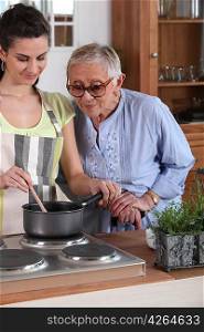 Young woman cooking for an elderly lady