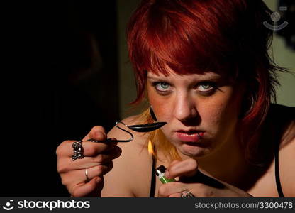 Young woman cooking heroin in a spoon