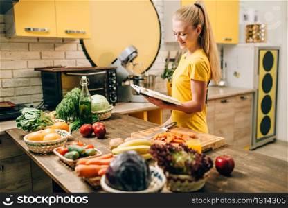 Young woman cooking on recipes, healthy eco food. Vegetarian diet, fresh vegetables and fruits. Young woman cooking on recipes, healthy eco food