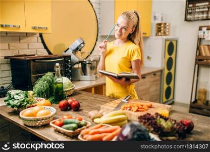 Young woman cooking on recipes, healthy eco food. Vegetarian diet, fresh vegetables and fruits. Young woman cooking on recipes, healthy eco food