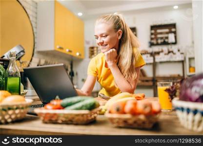 Young woman cooking on recipes, healthy food. Vegetarian diet, fresh vegetables and fruits. Young woman cooking on recipes, healthy food