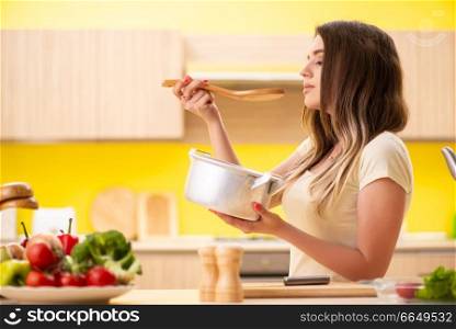 Young woman cooking soup in kitchen at home