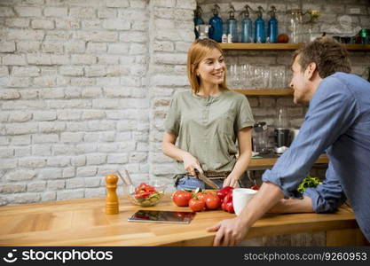 Young  woman cooking while man drinking coffee  in the rustic kitchen