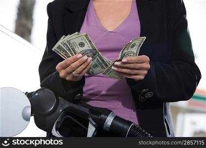 Young woman counting money at service station