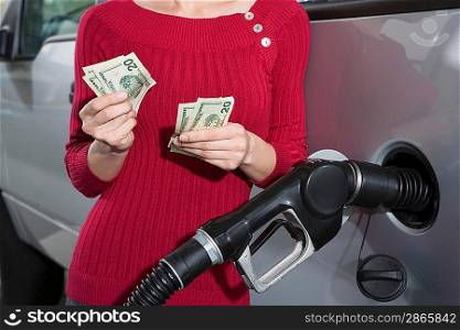Young woman counting money at service station