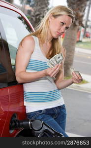 Young woman counting money at service station