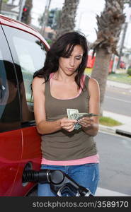 Young woman counting money at service station