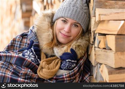 Young woman cover in blanket posing winter countryside wooden logs